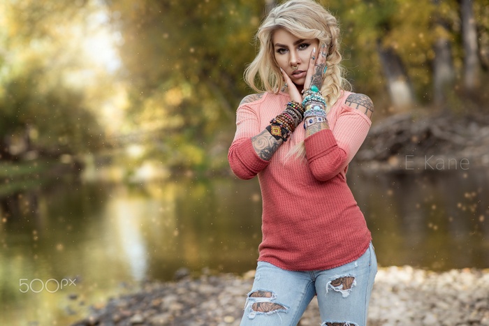 Woman with tattoos and bracelets by a river