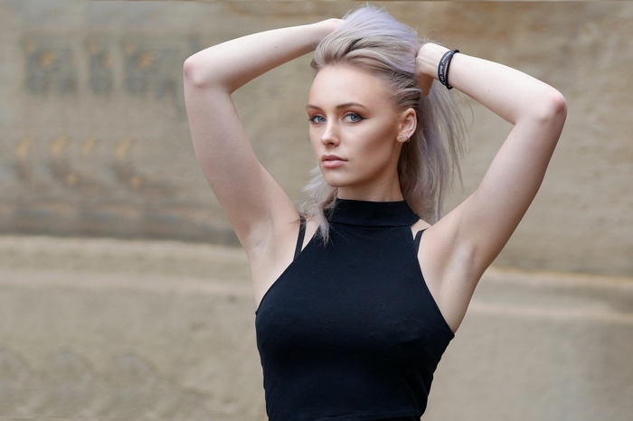 Woman with arms up, blonde hair, black top