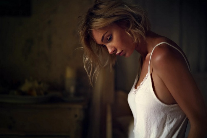Woman in white camisole looking down
