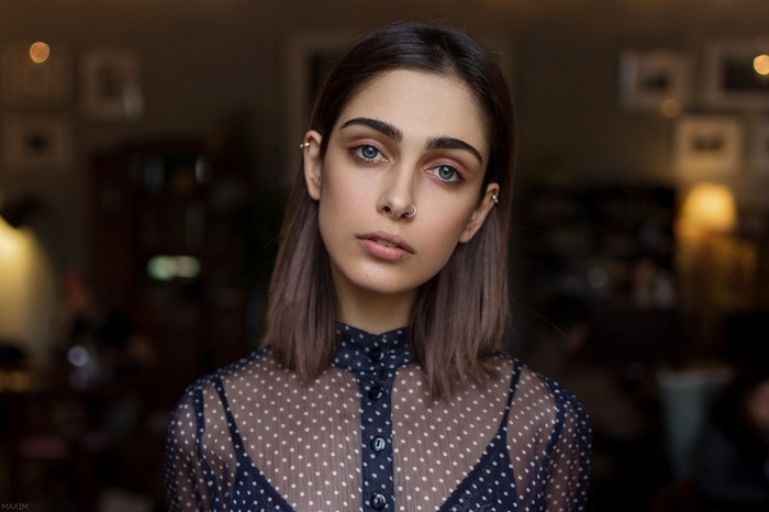 Woman with nose ring and piercings wearing polka dot shirt