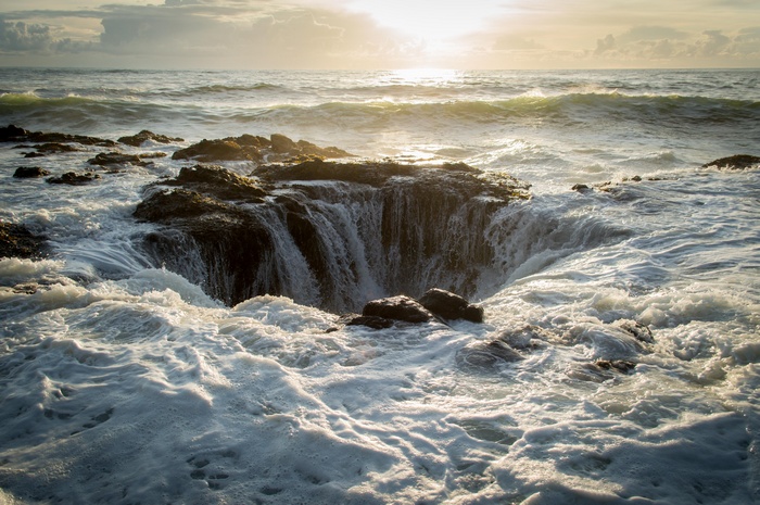 Ocean waves crashing into a rocky shore with a natural whirlpool