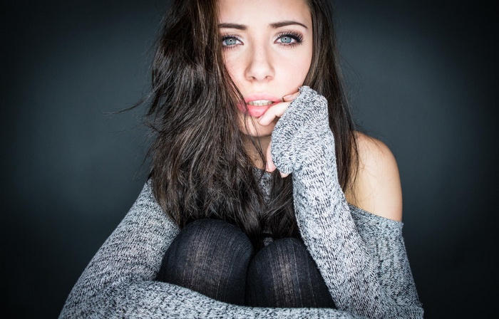 Woman with dark hair and blue eyes wearing a sweater