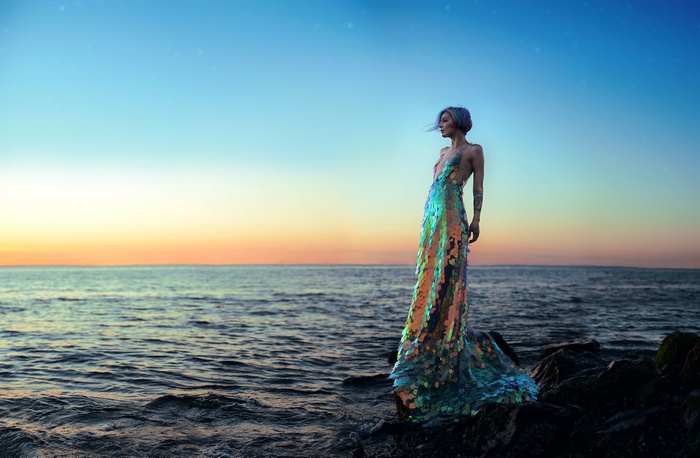 Woman in sequined dress by the sea at sunset