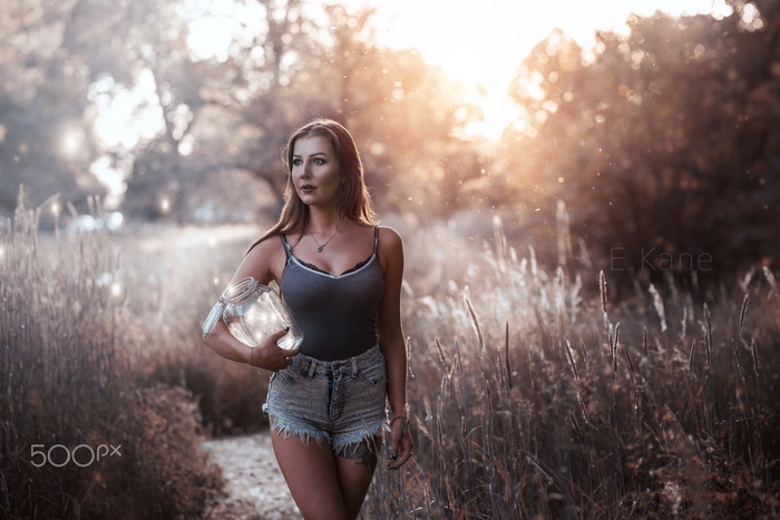 Woman holding a jar of lights in a field