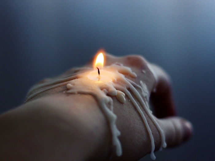 Candle wax melting on a hand with fire