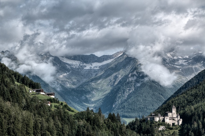 Castle and houses in a mountain valley with clouds