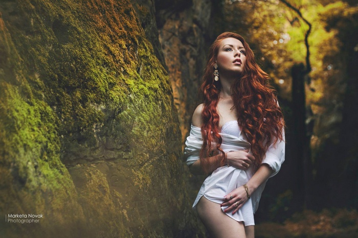 Redhead woman in white shirt by mossy rock