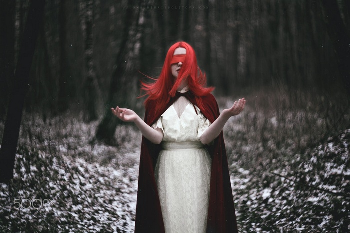 Woman with red hair and blindfold in forest