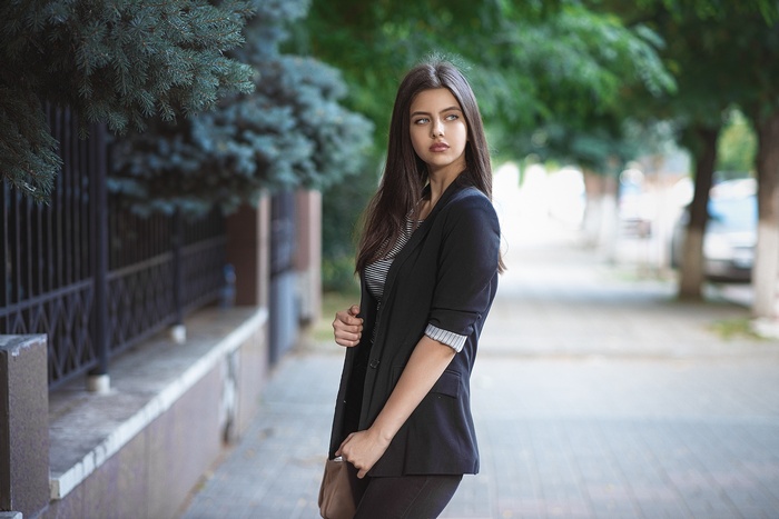 Woman in a black blazer standing outdoors