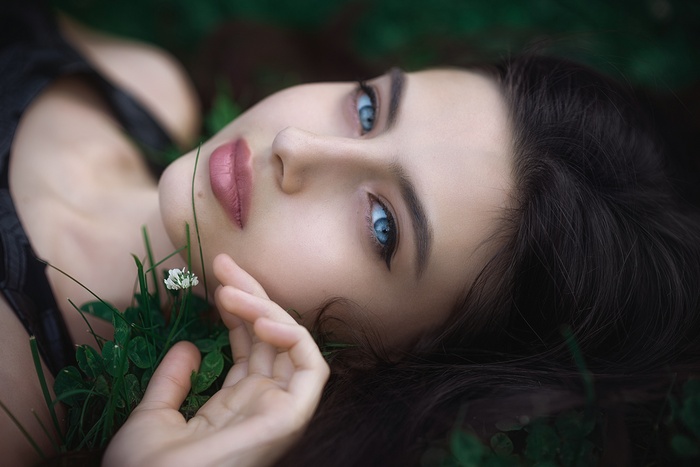 Woman with blue eyes lying in grass