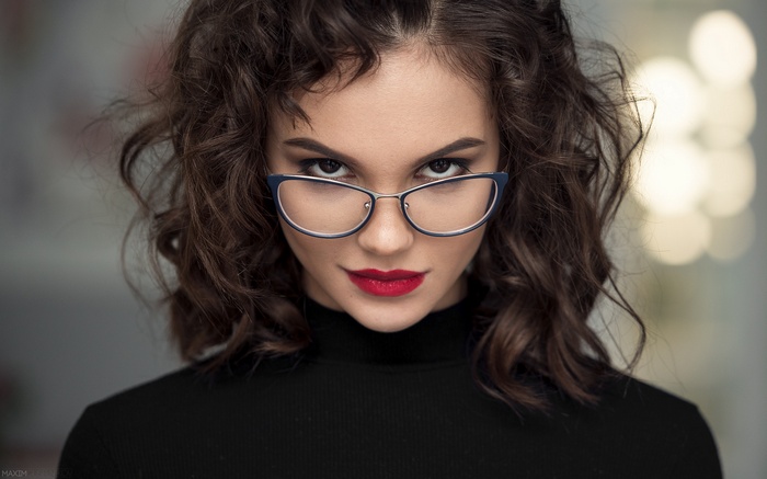 Woman with curly hair and glasses wearing red lipstick