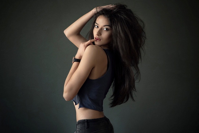 Woman with long dark hair wearing a watch and short top