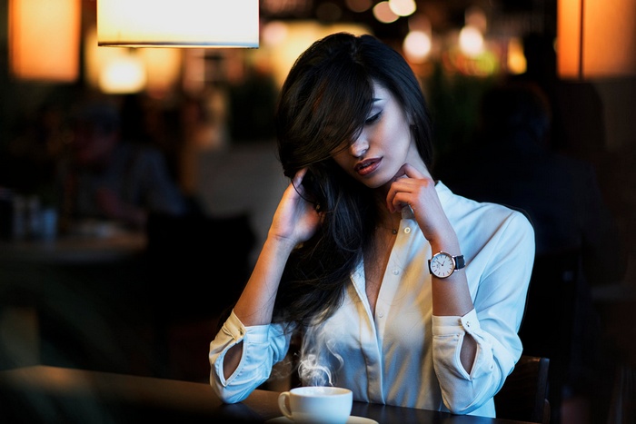 Woman with long dark hair wearing a white shirt and a watch