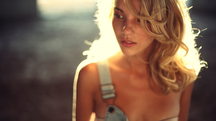 Woman with blonde hair and freckles wearing overalls