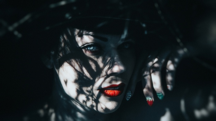 Woman with red lipstick and blue eyes in shadow