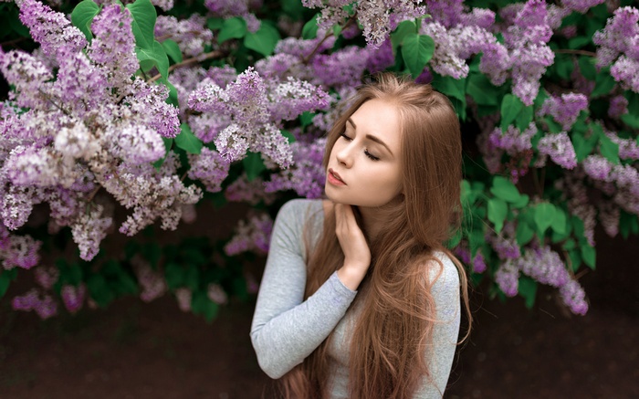 Woman with long blonde hair near lilac flowers