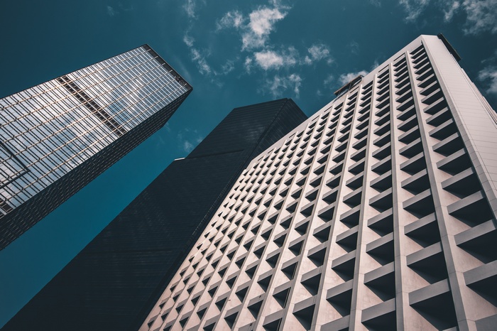 Three modern skyscrapers against a blue sky with clouds
