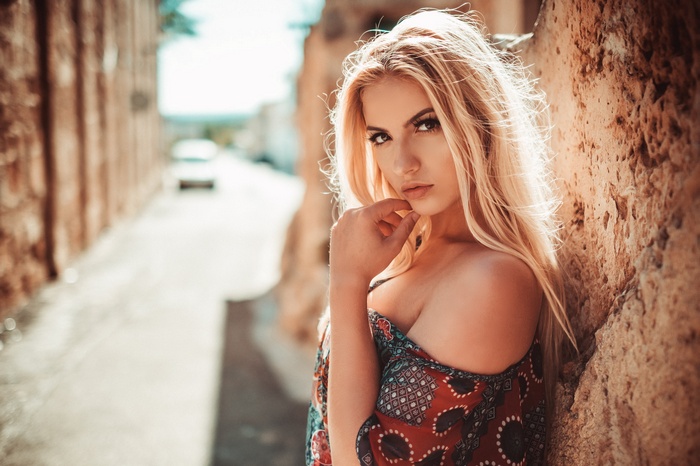Woman with blonde hair leaning against a wall