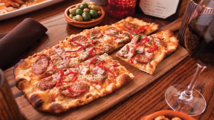 Flatbread pizza with salami and bell peppers, olives, and wine