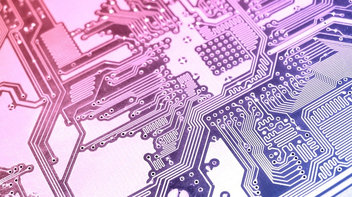 Close-up of a printed circuit board with pink and blue lighting