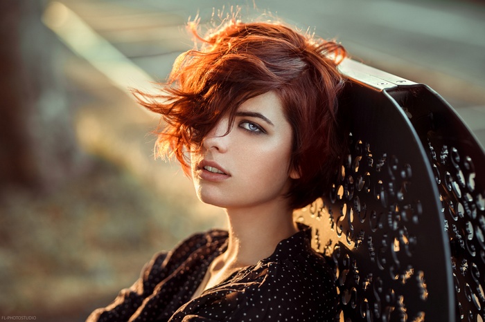 Woman with red hair leaning on a bench