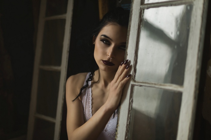 Woman with dark makeup and nose ring leaning on window