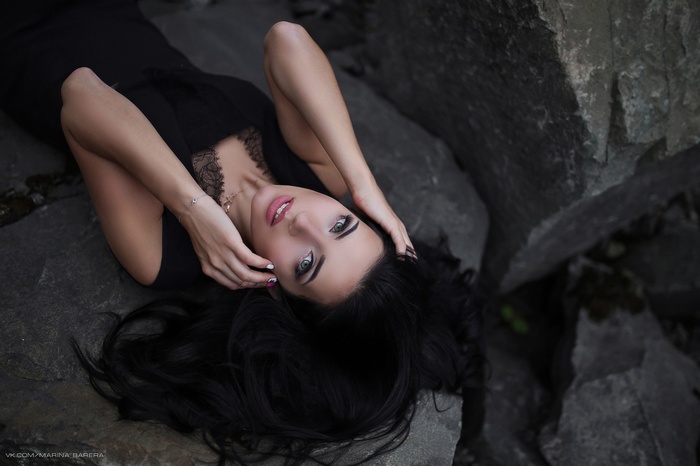Woman in black dress lying on rocks