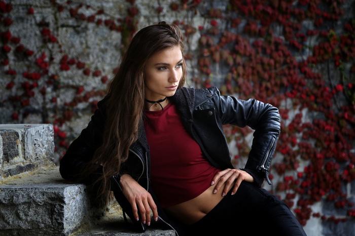Woman with long brown hair wearing a choker and leather jacket