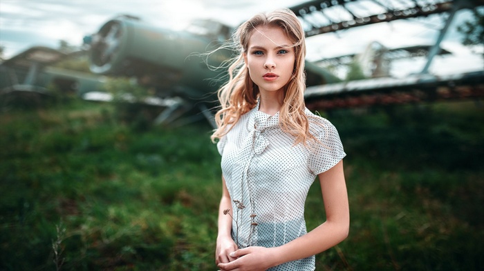 Woman with blonde hair in front of an abandoned aircraft