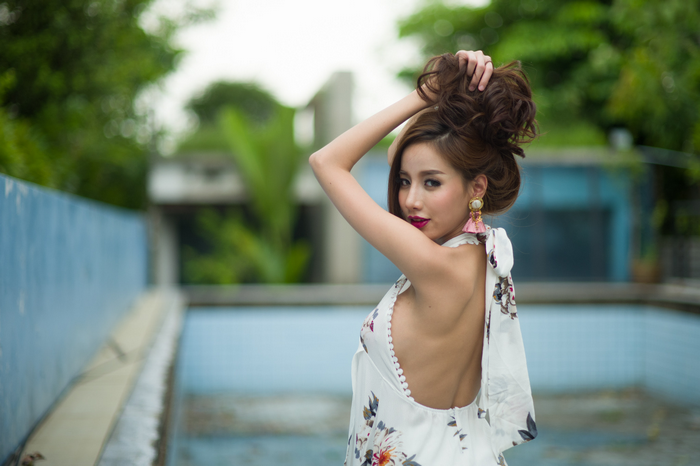 Asian model with hands in hair by pool