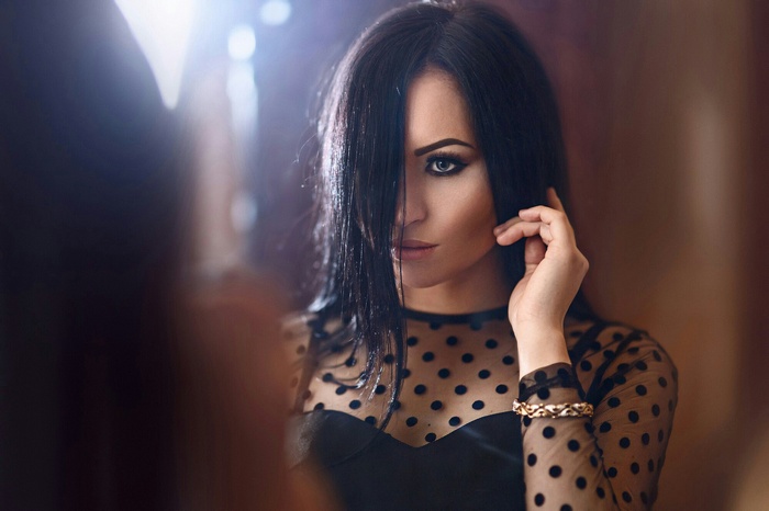 Woman with black hair and smoky eyes in a sheer polka dot top