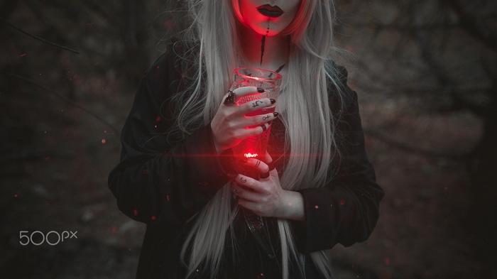 Woman with long blonde hair holding a glowing red glass