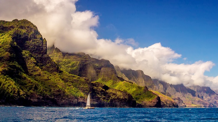 Sailboat on the ocean with Na Pali Coast mountains