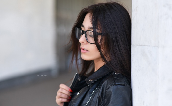 Woman with glasses and red nails wearing a leather jacket