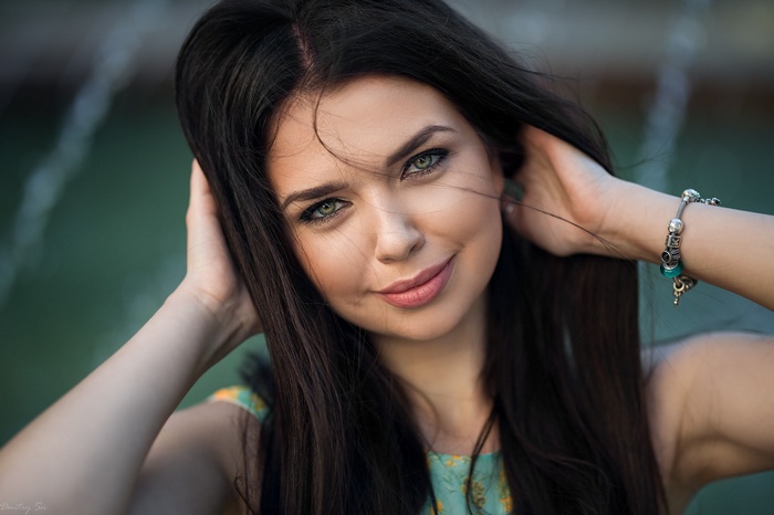 Woman with dark hair and green eyes smiling