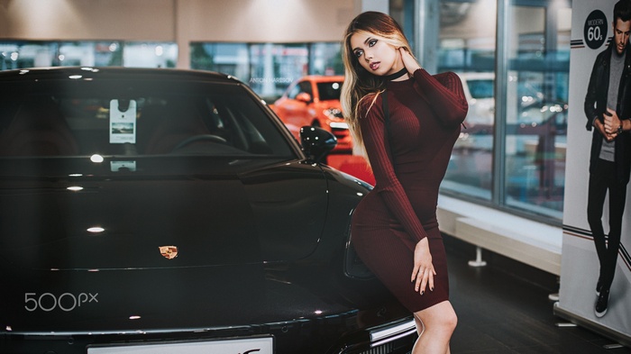 Woman in dress posing by a Porsche car