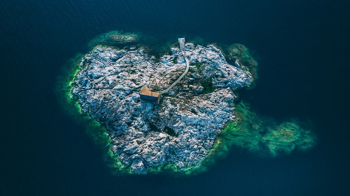 Aerial view of a rocky island with a small building and pier