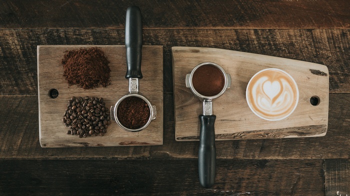 Coffee beans, ground coffee, and latte art on wood