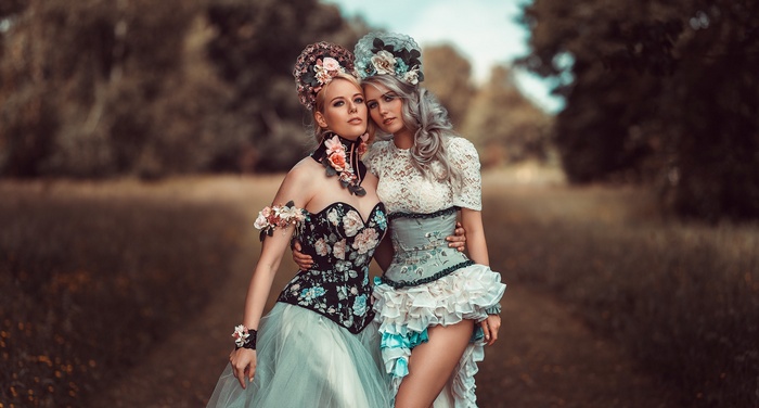 Two women in corsets and elaborate headdresses
