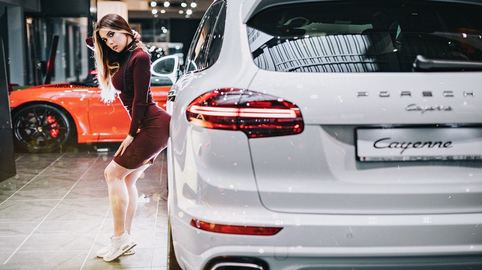 Woman in dress leaning against Porsche Cayenne