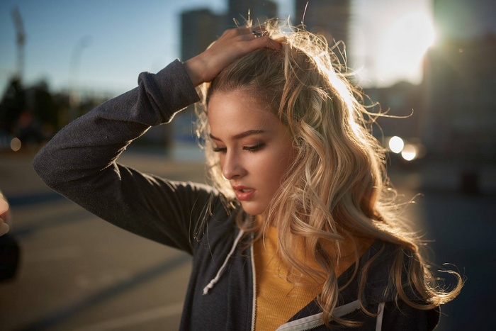 Woman with blonde hair touching her head outdoors