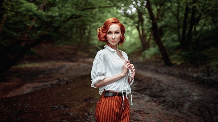 Redhead woman in white shirt and striped pants in forest