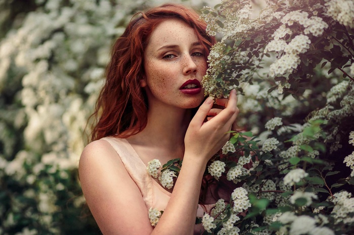 Redhead woman with freckles among white flowers