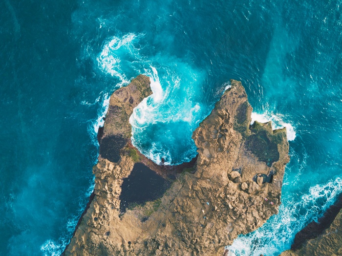 Aerial view of rocky coastline with turquoise ocean waves