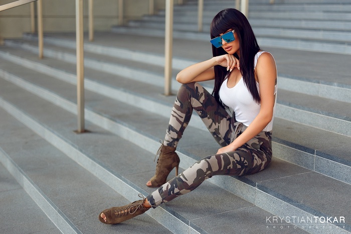Woman in camouflage pants and sunglasses sitting on stairs