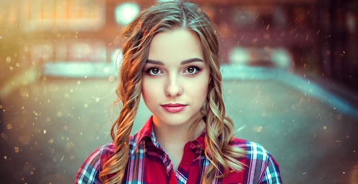 Portrait of a young woman with curly hair wearing a plaid shirt