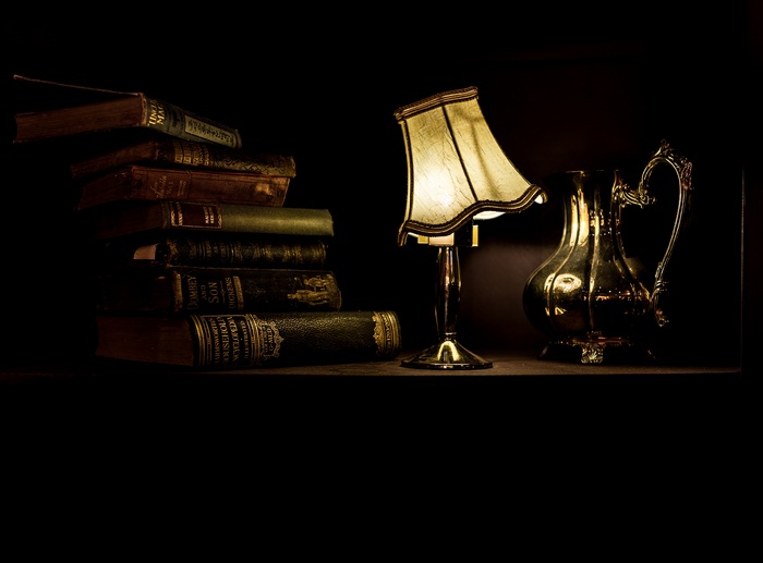 Stack of old books with a lamp and pitcher