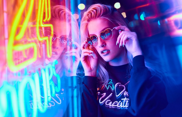 Woman with heart-shaped sunglasses in neon lights
