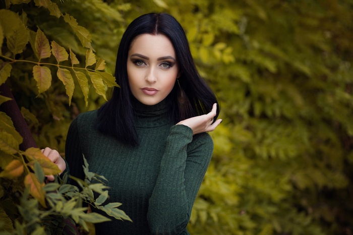 Woman with dark hair in a green turtleneck outdoors