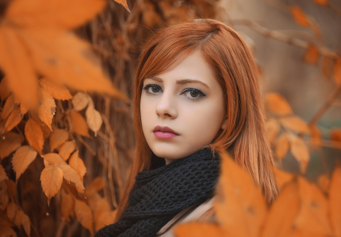 Redhead woman wearing a black scarf among autumn leaves